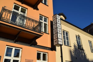 kamienice, fragment balkonu, neon z napisem PRAGA